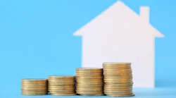 Stacks of coins in increasing order stand in front of a home, indicating equity