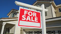 For sale sign posted in the front yard of a single-family home