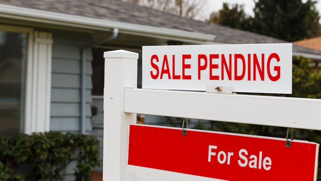 Sign posted in front yard showing a home sale is pending