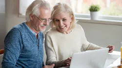 Baby Boomer couple looking at home listings on a laptop
