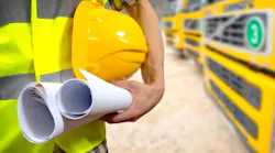 Construction worker holding plans and a hard hat Construction worker holding plans and a hard hat