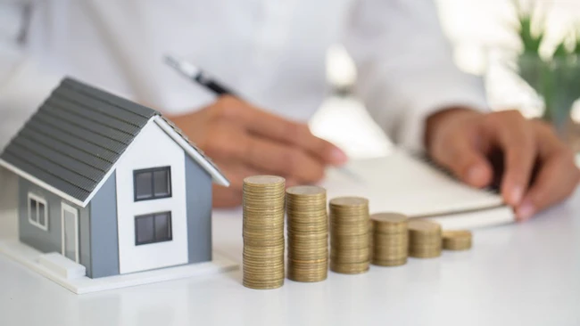 Stacks of coins next to a model home show home sales profits