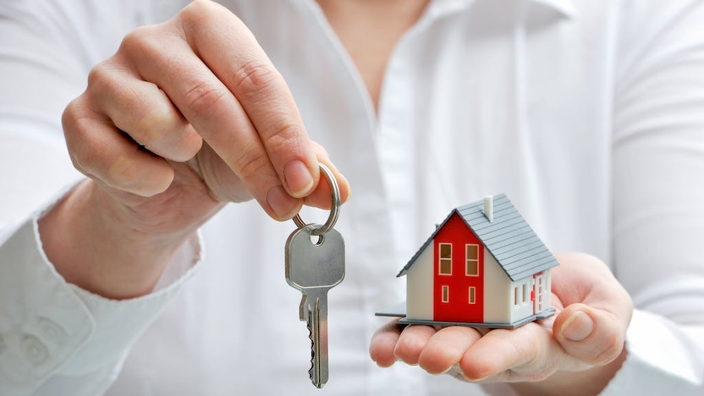 Real estate agent holds up key and model home