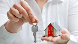 Real estate agent holds up key and model home Real estate agent holds up key and model home