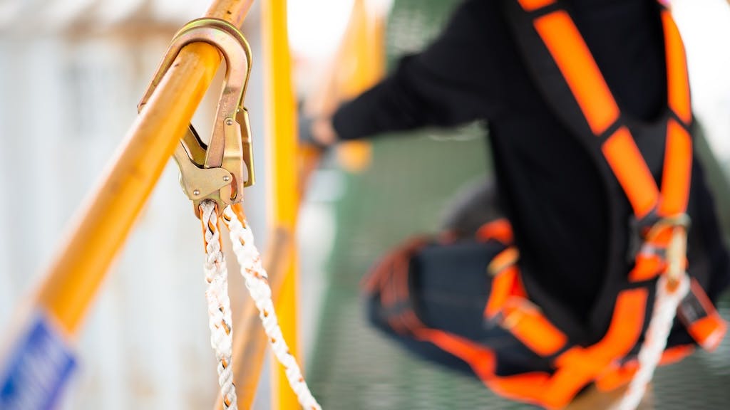 Worker uses harness to prevent falling while on a scaffolding