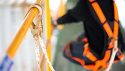 Worker uses harness to prevent falling while on a scaffolding Worker uses harness to prevent falling while on a scaffolding