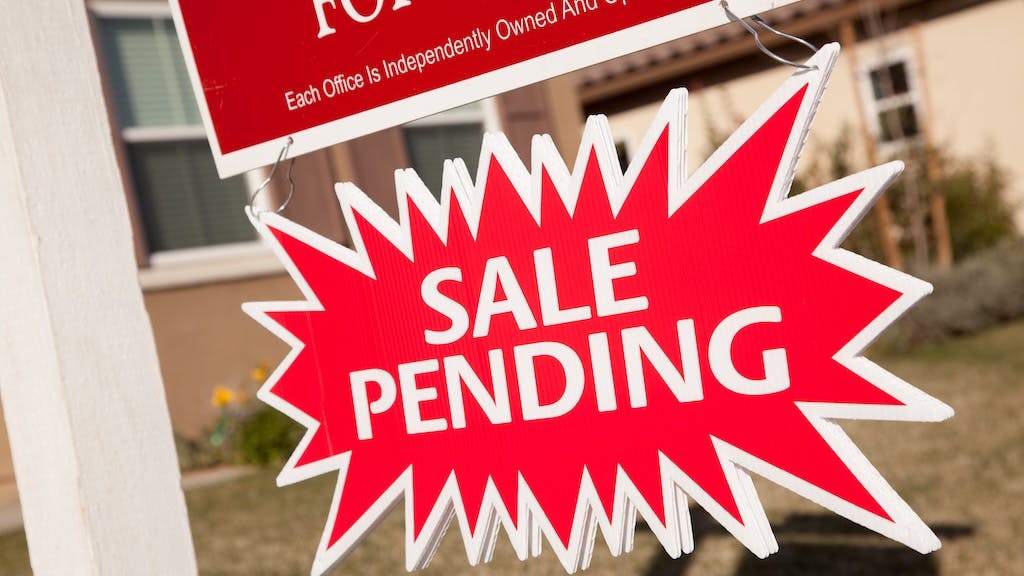 Pending sale sign posted in a front yard