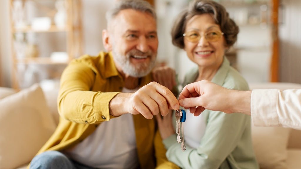 Baby Boomers accepting house keys from a real estate agent