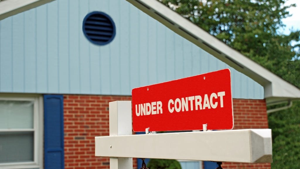 A sign reading 'Under Contract' posted in front of a house