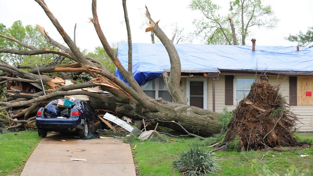A tree laying on a home in the aftermath of a tornado