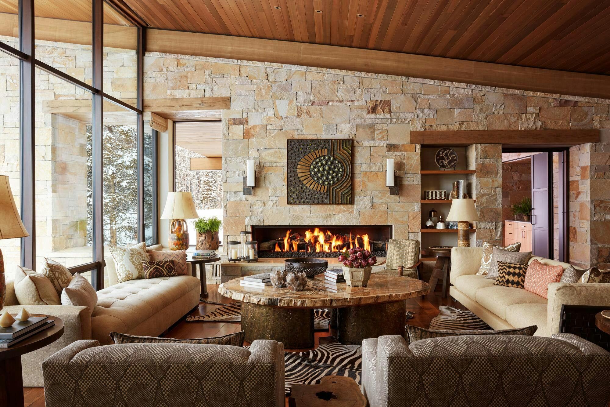 This Big Sky, Mont., living room by Reid Smith Architects showcases an inviting look with warm stone walls, wood details, and earthy furnishings.