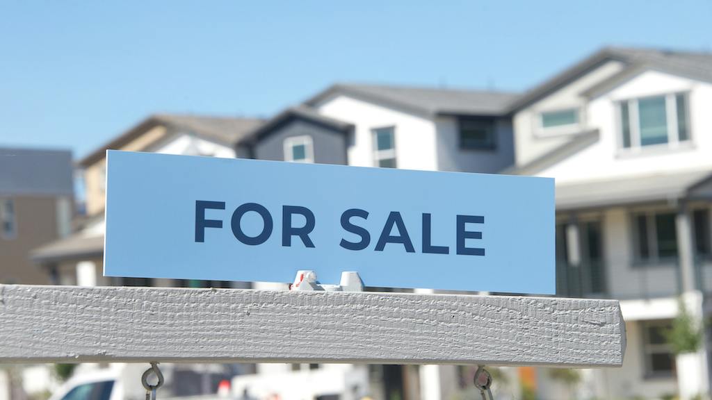 'For Sale' sign in front of a new-home community