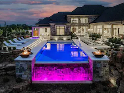 This estate home in Indiana features multiple indoor-outdoor living experiences, including an infinity-edge pool equipped with a slide that empties into a second pool along the home's side yard.